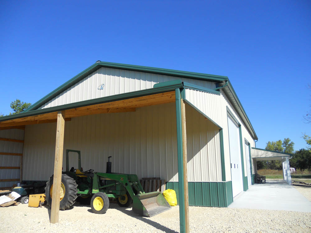 Tan and grene metal building with a covered area with a tractor