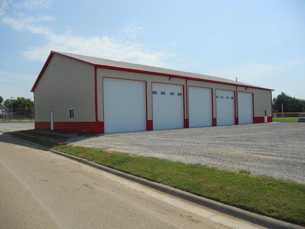 Tan and red metal building with 5 large overhead doors