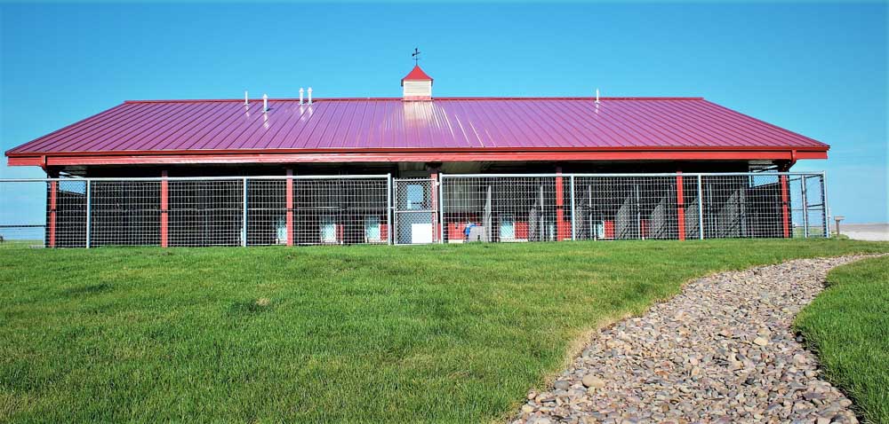 Red metal stable with fence around it